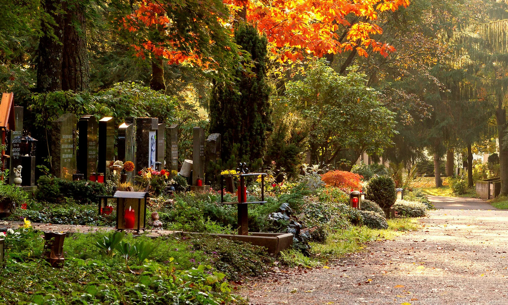 Weg, der über den Friedhof führt mit schön geschmückten Gräbern bei Herbst
